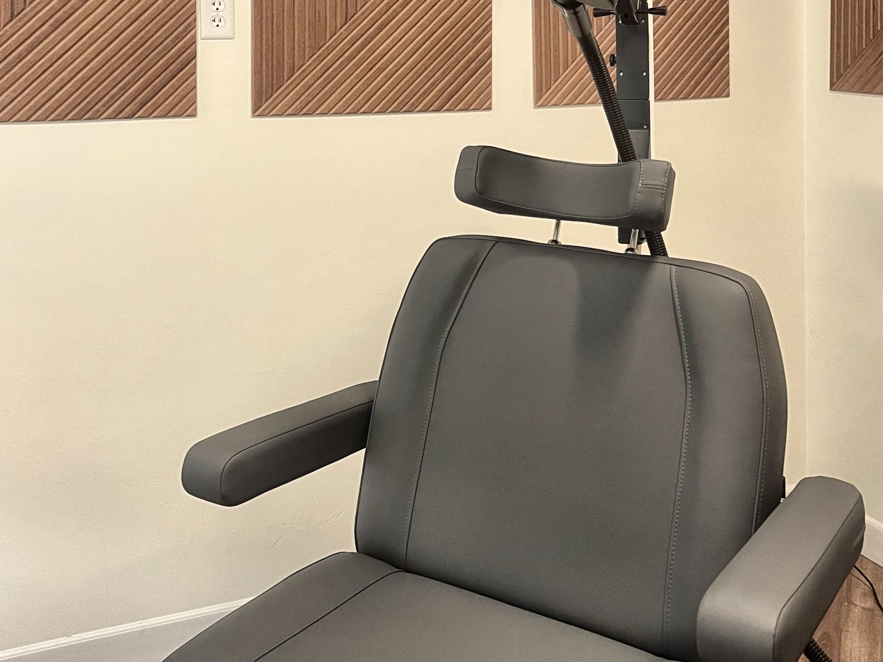The TMS treatment chair with the cushioned headrest and coil arm.