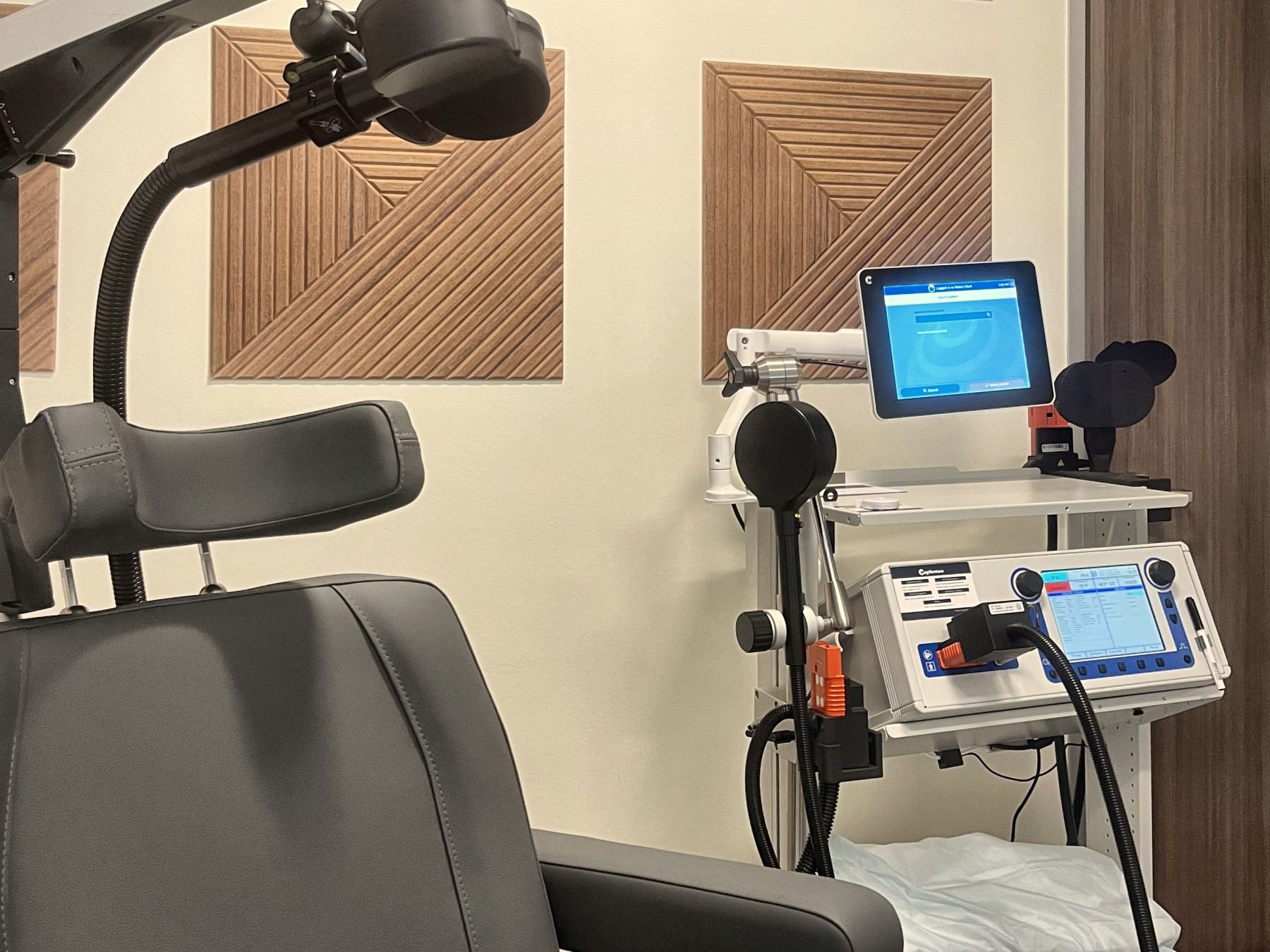 The TMS coil and stimulator cart beside the treatment chair.