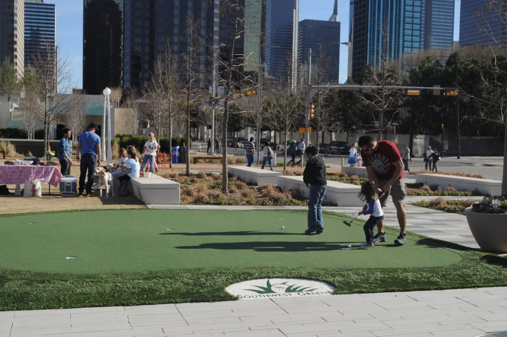 Visitors spending time outdoors at Klyde Warren Park, with Dallas buildings behind them.