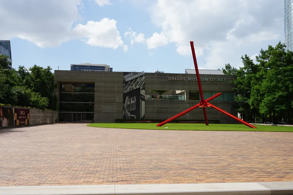 The Dallas Museum of Art entrance and red outdoor sculpture, surrounded by trees.